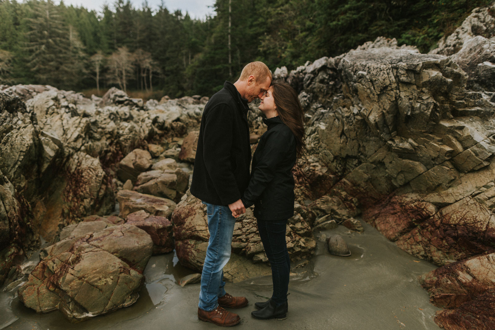 Couple holding hands and touching foreheads in Tofino BC