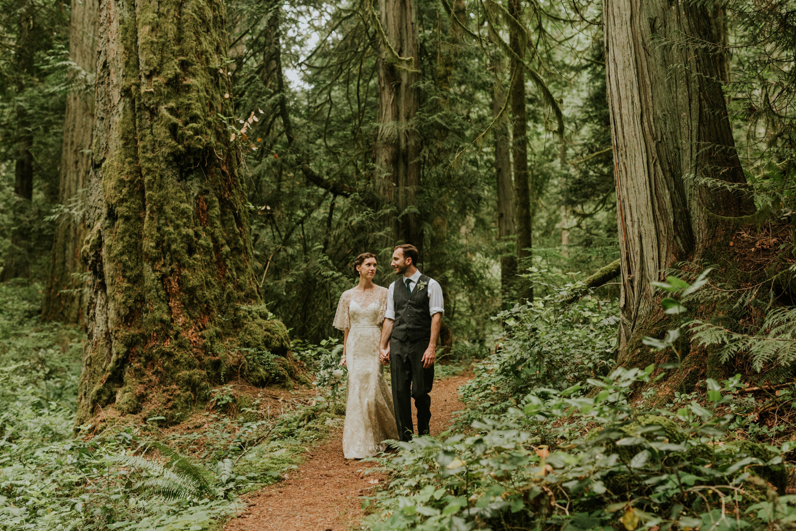 Bride and groom walking through an old growth forest